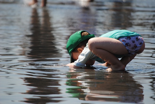 水たまりで遊ぶ男の子が水の中をのぞいている写真